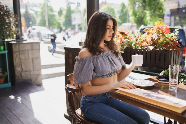 Kaunis nuori nainen juo teetä ravintolassa — kuvapankkivalokuva