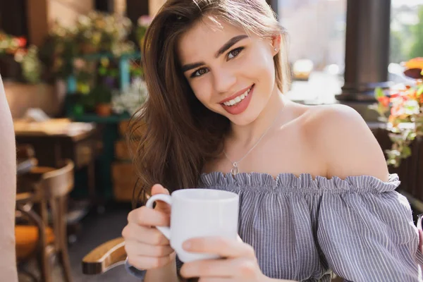 Pen ung dame som smiler mens hun har te i restauranten. – stockfoto