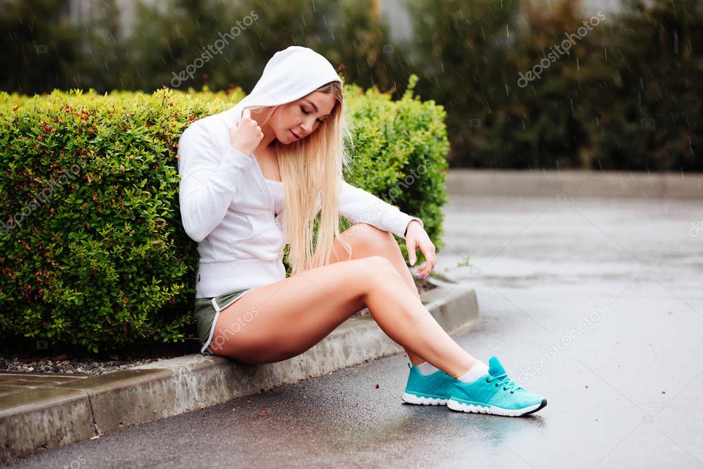 Yağmur başlık altında oturan spor giyim sportif seksi kız 