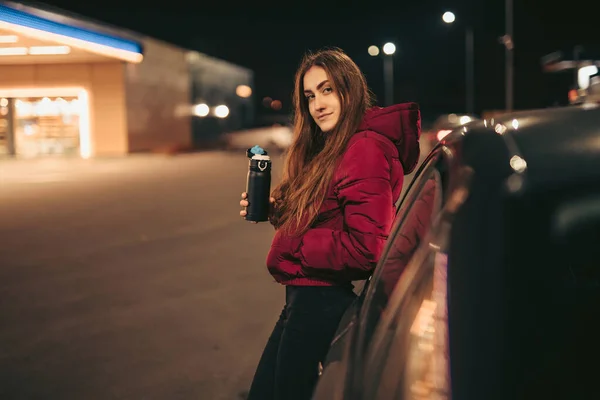 Női sofőr portréja termoszos üveggel a benzinkútnál, éjszaka — Stock Fotó
