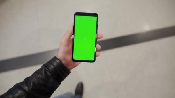 POV, мужчина держит в руке смартфон с зеленым экраном, гуляя в грязи — стоковое видео