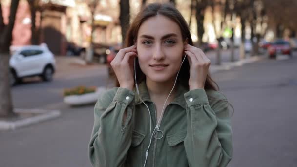 European woman puts on earphones and listening to music in urban city — Stock Video