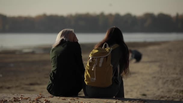 Zwei Freundinnen sitzen am Fluss und unterhalten sich miteinander — Stockvideo