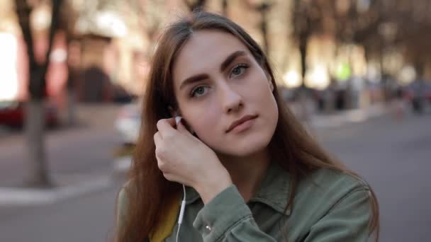 Mujer europea se pone auriculares y escucha música en la ciudad urbana — Vídeo de stock