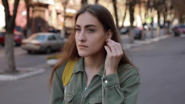 在城市里，欧洲女人戴上耳机听音乐 — 图库视频影像