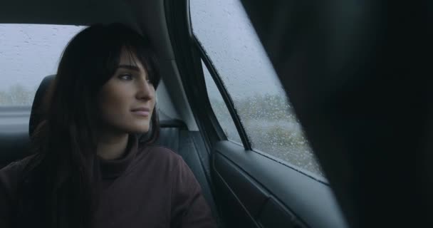 Woman thinking sitting in a car at rainy day looking at window — Stock Video