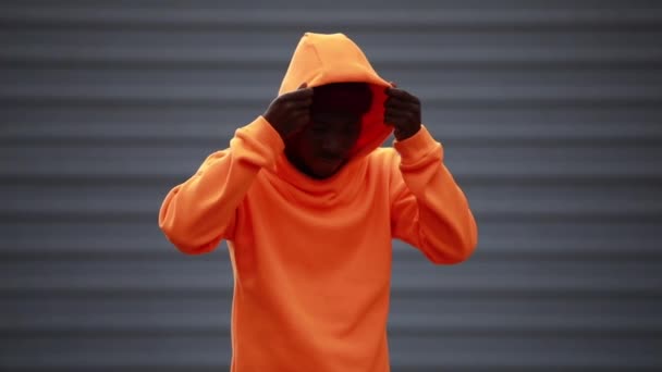 Hombre africano guapo y fresco con sudadera con capucha naranja brillante — Vídeo de stock