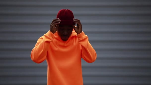 Knap en cool Afrikaanse man draagt heldere oranje hoodie — Stockvideo
