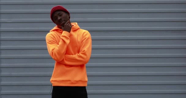 Hombre africano guapo con sudadera con capucha naranja brillante mostrando gestos bien — Vídeo de stock