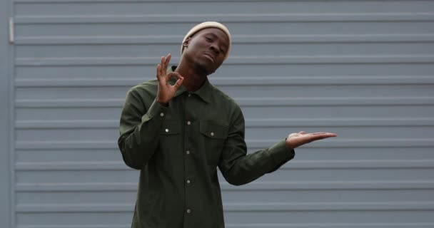 Knappe Afrikaanse man demonstreert een product met verschillende gebaren — Stockvideo