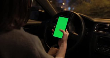 Pov, gece vakti arabada yeşil ekranlı akıllı telefonu tutan kadın.