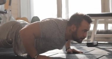 Spor salonunda egzersiz yapan ve şınav çeken bir adam.