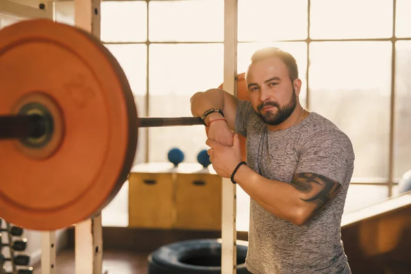 Retrato de homem forte com barra em um ginásio de fitness — Fotografia de Stock