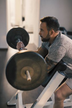 Ez bar vaiz kıvrımlı, pazı egzersizi yapan bir adam.