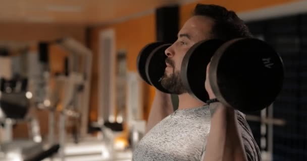 Mann hebt Hanteln in Fitnessstudio und macht Übungen für Deltas — Stockvideo