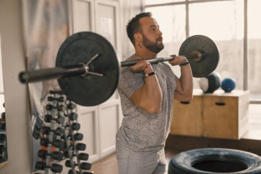 Spor salonunda halterli bir adam çömeldi.