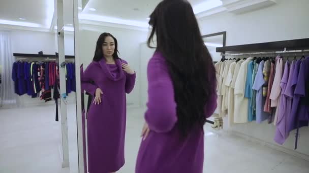 Покупательница примеряет фиолетовую шубу в бутике — стоковое видео
