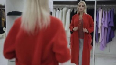 Kadın alıcı butikte kırmızı kürk manto dener. 