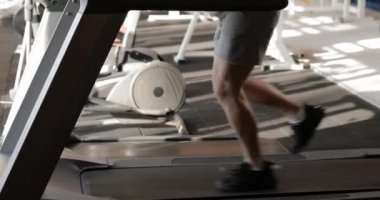 Spor salonunda koşu bandında koşan bir adam