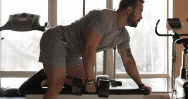 Salonda dambılı kaldıran adam latissimus dorsi için egzersiz yapıyor.