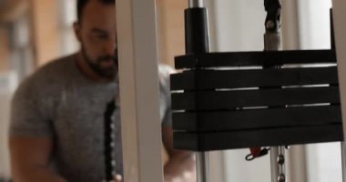 Spor salonunda egzersiz yapan bir adam triseps kaslarını güçlendirir.
