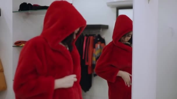 Покупательница примеряет красную шубу в бутике — стоковое видео