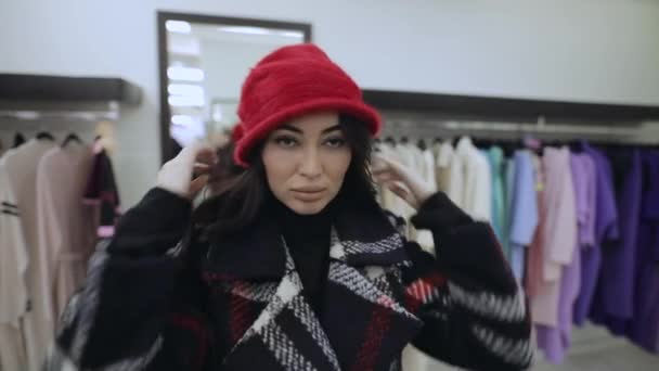 Mujer comprador Pruébate el sombrero rojo en la boutique — Vídeo de stock