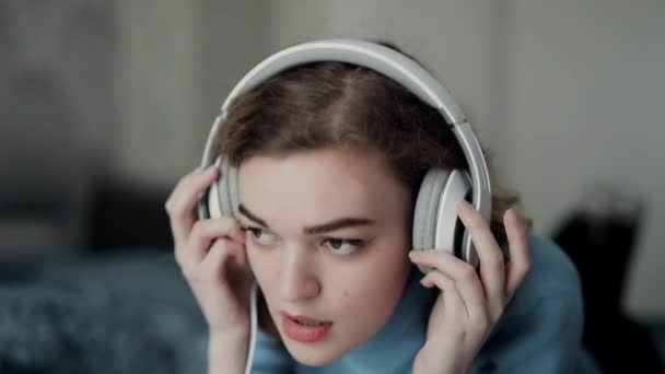 Vrouw die thuis naar muziek luistert in een grote hoofdtelefoon — Stockvideo