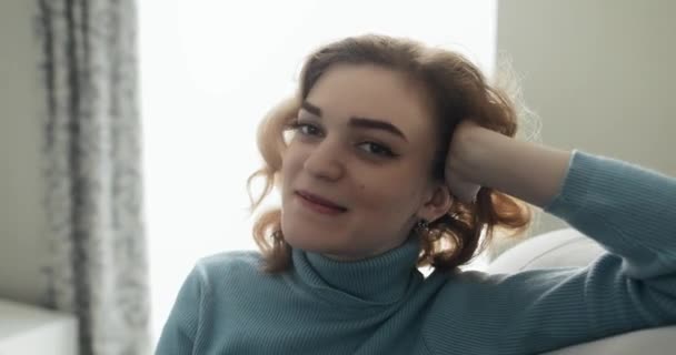 Pěkná mladá koketka sedící na útulné pohovce a povídající si se mnou — Stock video