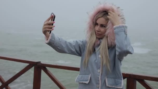 Женщина делает селфи с мобильным телефоном у моря — стоковое видео
