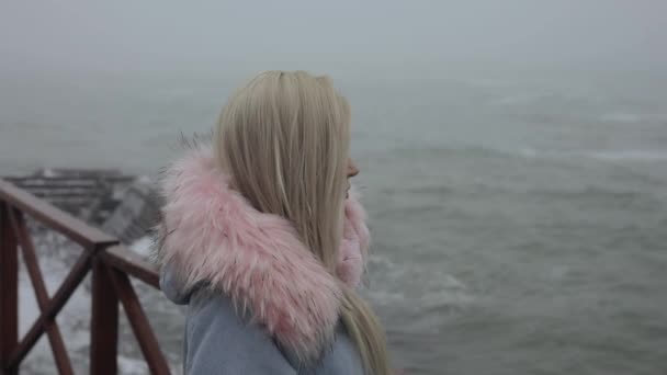 Kalmte, vrouw die kijkt naar de zee golven dragen kap — Stockvideo