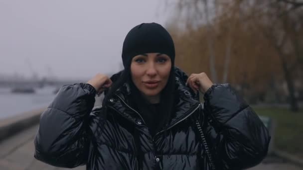 Стильна жінка, що йде біля берега річки взимку — стокове відео