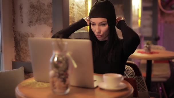 スタイリッシュな女性は、カフェでラップトップを探して帽子を着用 — ストック動画