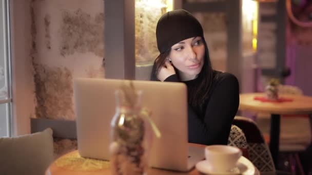 Stylische Bloggerin, die im Café am Laptop arbeitet, setzt Kopfhörer auf — Stockvideo