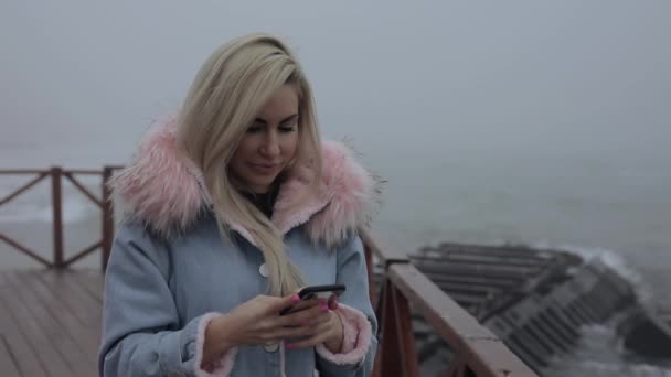 Femme utilisant un téléphone mobile près de l'océan SMS message — Video