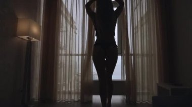 Seksi kadın silueti Sabah perdeleri açar