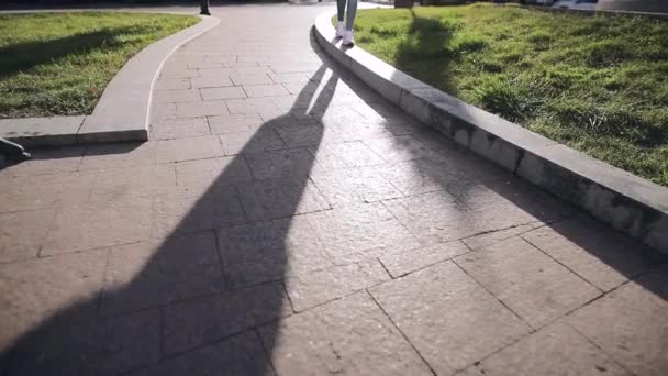 Schaduw van vrouwelijke benen loopt op een grond — Stockvideo