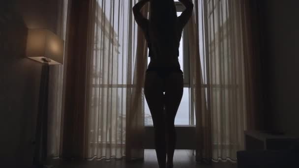 Silhouette di donna sexy apre le tende al mattino — Video Stock