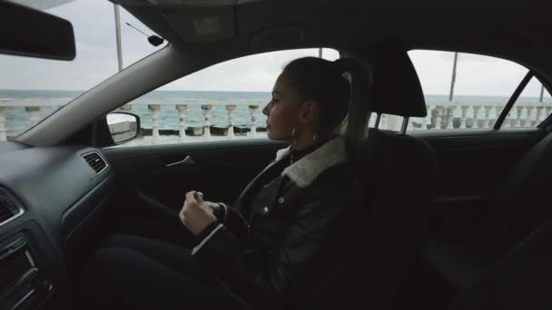 Woman passenger puts on wireless earphones sitting in a car — 비디오