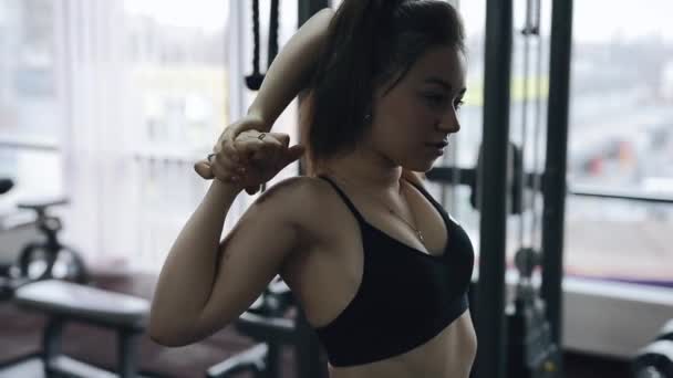 Mujer calentando sus músculos en el gimnasio — Vídeos de Stock