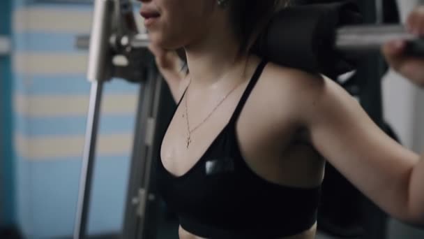 Jonge vrouw maakt squats met lange halter in de sportschool — Stockvideo