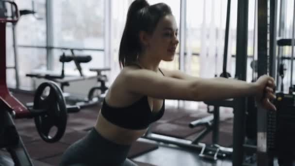 Kvinnan värmer upp musklerna i gymmet — Stockvideo