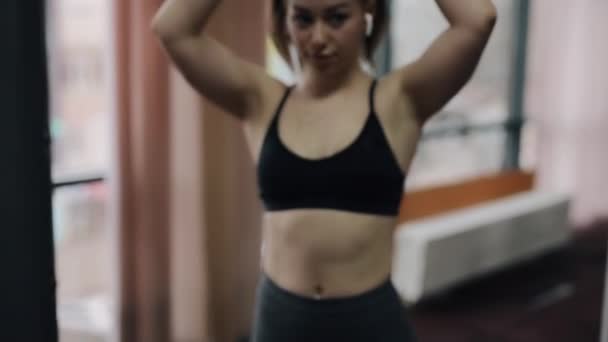 Mujer joven haciendo ejercicio en el aparato de entrenamiento en el gimnasio — Vídeo de stock