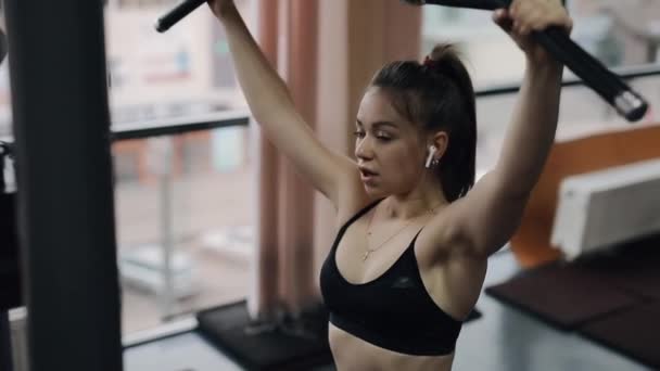 Mujer joven haciendo ejercicio en el aparato de entrenamiento en el gimnasio — Vídeos de Stock
