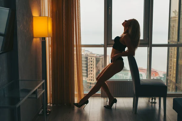 รูปแบบของผู้หญิงเซ็กซี่ที่น่าสนใจ โพสอยู่ใกล้หน้าต่างในอพาร์ทเม้นท์ — ภาพถ่ายสต็อก