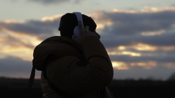 Gün batımında kulaklık takan bir adamın silueti. — Stok video