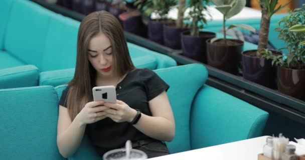 Kobieta siedzi w kawiarni i pisze smsy. — Wideo stockowe