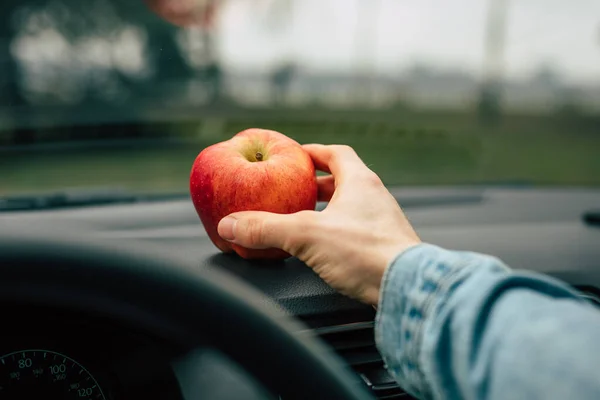 Kevyt omena välipala autossa, käsi ottaa kypsiä hedelmiä — kuvapankkivalokuva