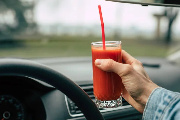 Man driver holding tomato juice in a car
