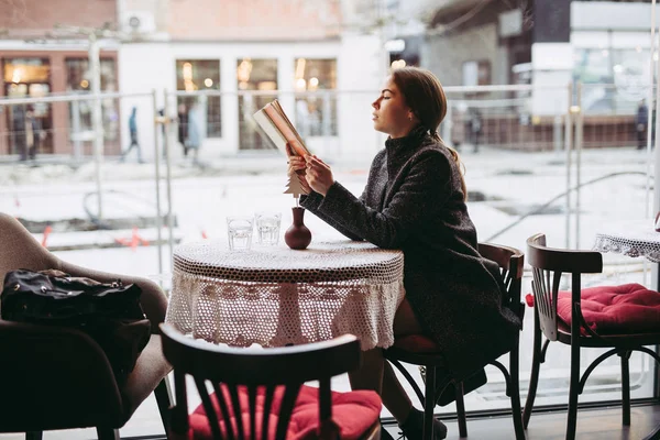 Jonge vrouw die boek leest in café — Stockfoto